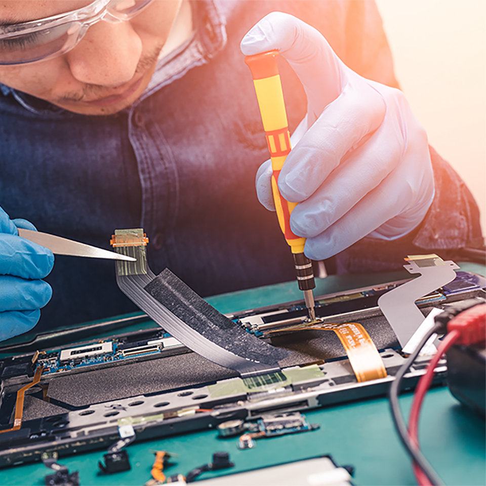 worker assembling a device using a soldering gun